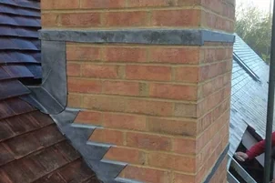 Brick chimney surrounded by slate roofing with neatly installed lead flashing, Apex Roofing Services Bournemouth