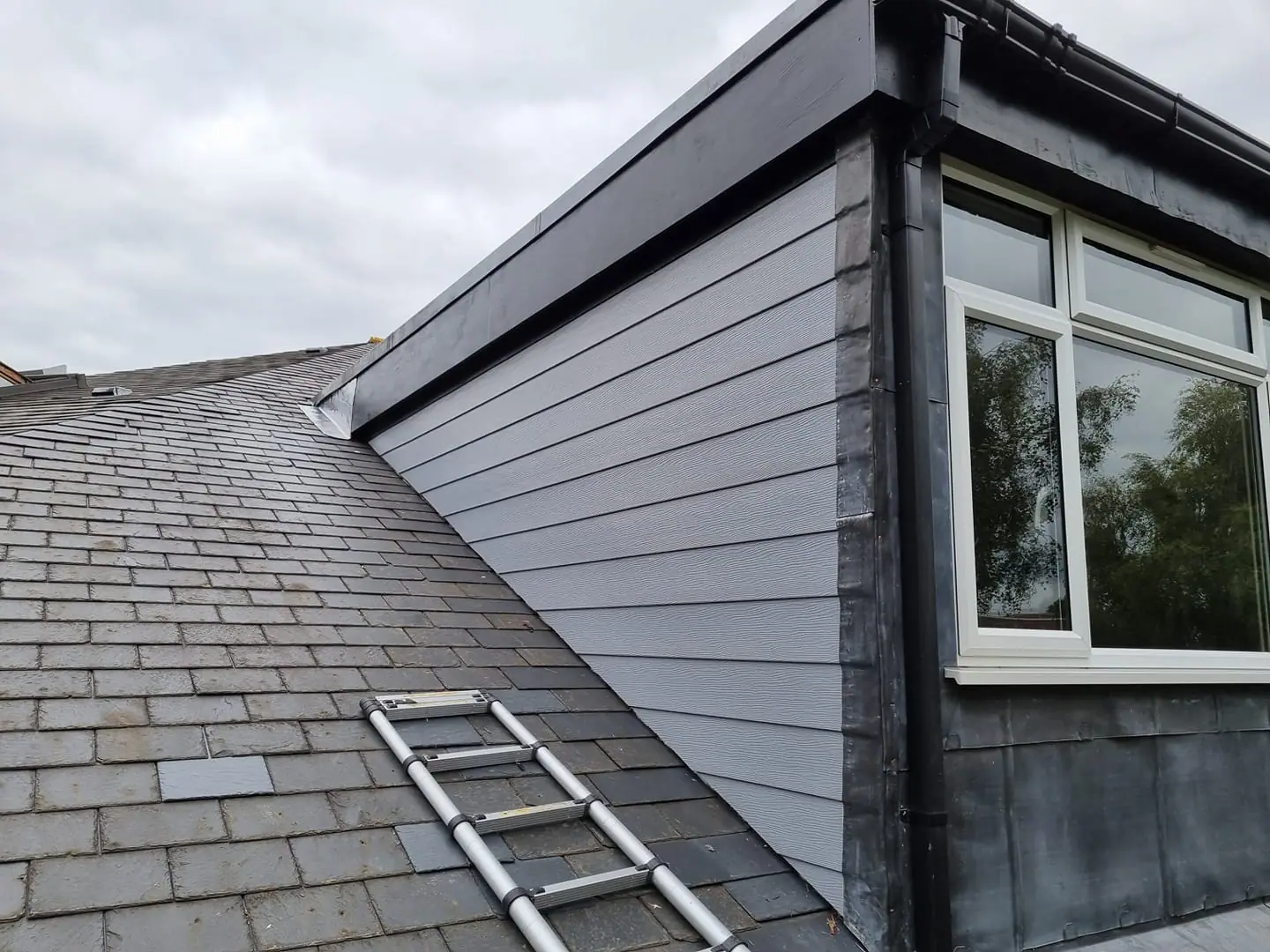 Grey slate roof with a loft extension window maintained by Apex Roofing Services Bournemouth